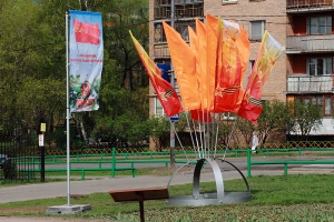 Флаг с праздничной символикой на мобильном флагштоке и декоративная флаговая конструкция Костер